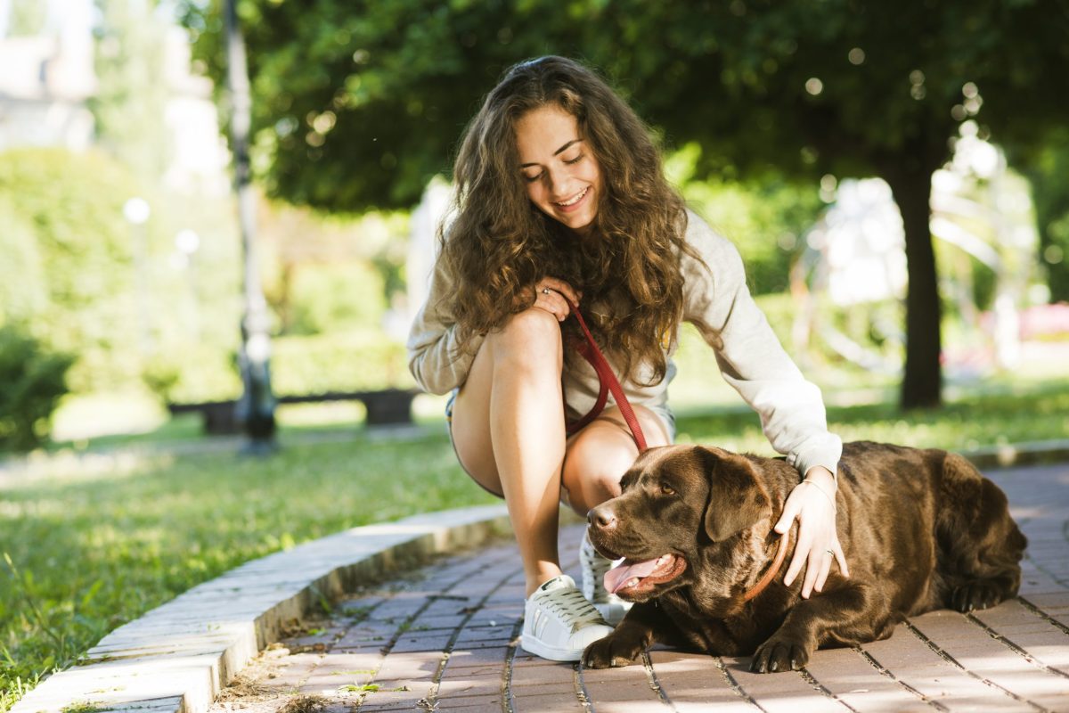 happy-woman-stroking-her-dog-park